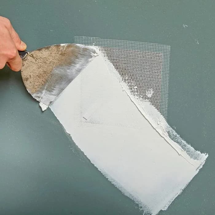 Drywall patch compound being applied over mesh for Mor Handy drywall repair